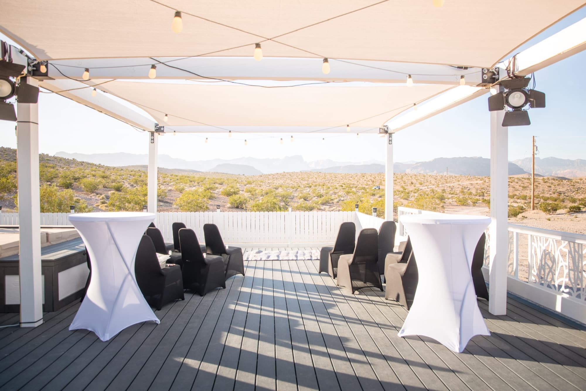 Daytime upper deck with retractable shade sail, string lights, and cocktail tables