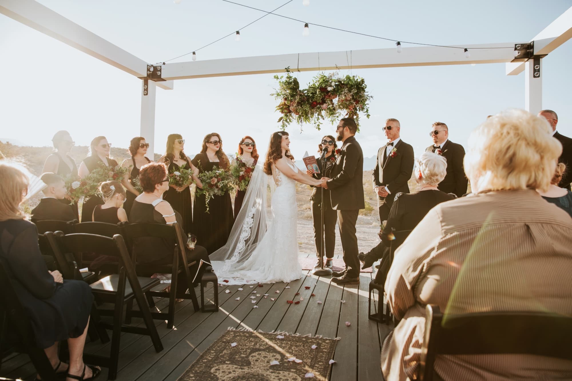 Wedding ceremony under a floral arch with the wedding party and seated guests